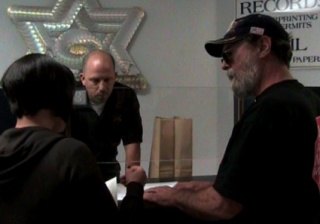 Bruce Olson (right) visits the Sheriff’s office to retrieve his confiscated possessions. Also pictured are paralegal Kayleen Bystrom and WESTNET employee Brian Borcherding.