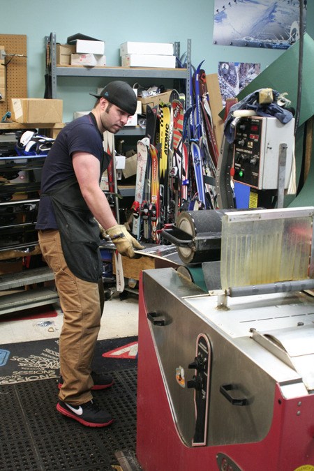 Kitsap Sports employee Sean Langaker grinds a snowboard to smoothen any nicked up ridges and scratches.