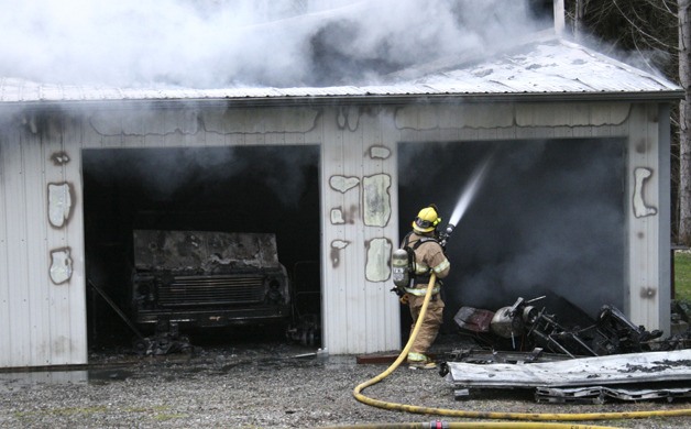 A firefighter sprays down the metal sides of a pole building Wednesday off Mainland View Lane.