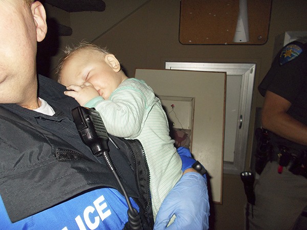 Bremerton police officer Frank Shaw holds a baby that he and other officers rescued early in the morning of Saturday