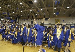 Bremerton High School seniors throw their caps into the air in celebration after graduating June 13 at the Pavilion at the Kitsap County Fairgrounds.