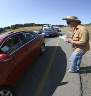 Tracey Williams passes out flyers to motorists at the State Route 3 Kitsap Way exit in an effort to spread awareness on ways to help panhandlers get on their feet.