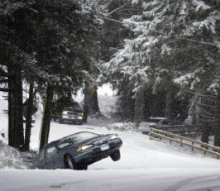 A stranded driver waits in his car as it sits in the ditch tilted above the ground on Tracyton Boulevard NW last week.