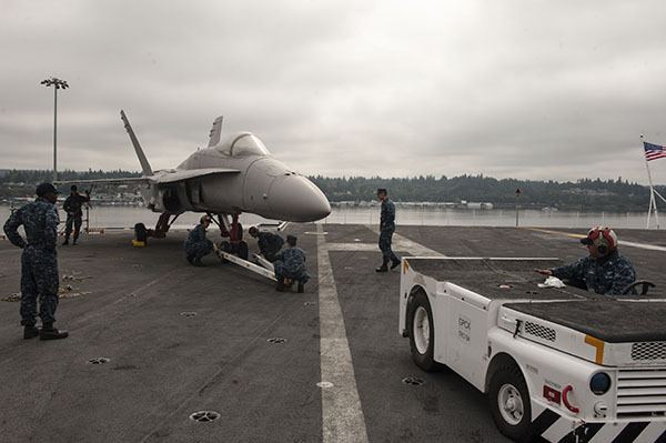 Sailors aboard Nimitz-class aircraft carrier USS John C. Stennis (CVN 74) attach an F/A-18 Hornet training dud to an aviation tow cart on the flight deck. Stennis is currently undergoing a Docking Planned Incremental Availability maintenance period at Puget Sound Naval Shipyard and Intermediate Maintenance Facility.