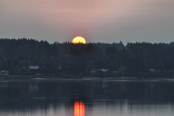 Haze from wild fires filters the sun as it rises from due east over Central Kitsap and Dyes Inlet Tuesday morning. Wildfires burning in the Cascades west of Wenatchee filled the atmosphere with haze and low-level easterly winds pushed the smoke over the Cascades through Snoqualmie Pass. The National Weather Service expected smoke to reach down into the Western Washington foothills by Tuesday afternoon.