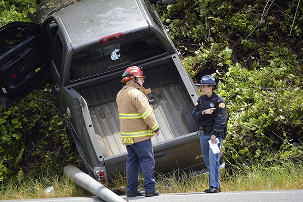 A firefighter and a Washington State Patrol trooper consult at the scene of a collision on Highway 305 near the Longhouse Texaco