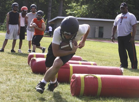 Central Kitsap’s Jared Vigil runs the ball during the team’s conditioning drills with assistant coach Hugh McKinnis on June 13.