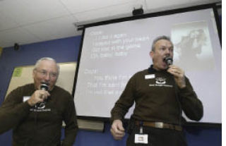 Kitsap Credit Union (KCU) President/CEO Elliot Gregg (right) and Senior Vice President of Marketing Ron Rogerson sing Britney Spears’ “Oops I Did It Again” in front of fellow employees Tuesday morning. KCU employees voted for who they thought could sing the best. The person with the most votes could match that number in money and buy themselves out of singing. The next person in line had the choice of matching the person in front of them and their total or sing. Gregg chose to sing over paying $355 while Rogerson offered his talents as a backup singer. All proceeds were donated to United Way of Kitsap County.