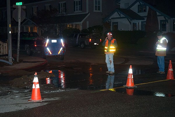 Workers stand near a buried ruptured sewer line in Old Town Silverdale Friday night. According to Andrew Nelson