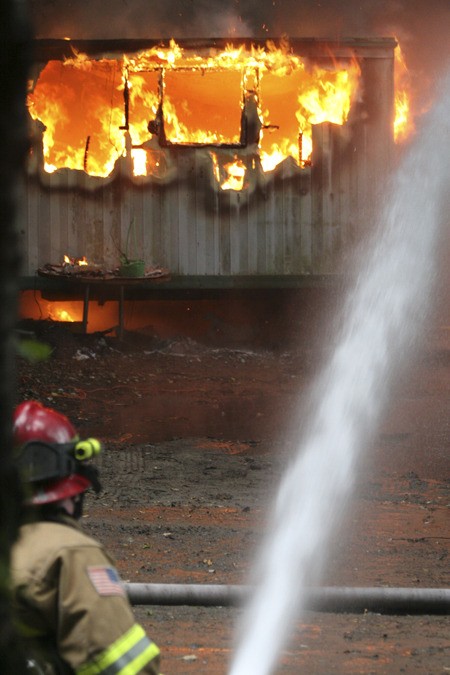 A firefighter douses flames at a residential fire Thursday afternoon off State Route 305.