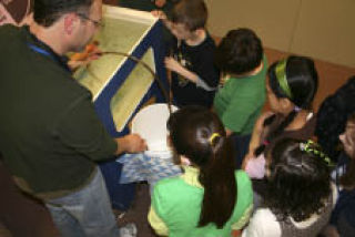 Woodlands Elementary School learning specialist Jeff Sullivan helps fourth-graders clean the school’s salmon tank Tuesday as part of the Salmon in the Classroom program.