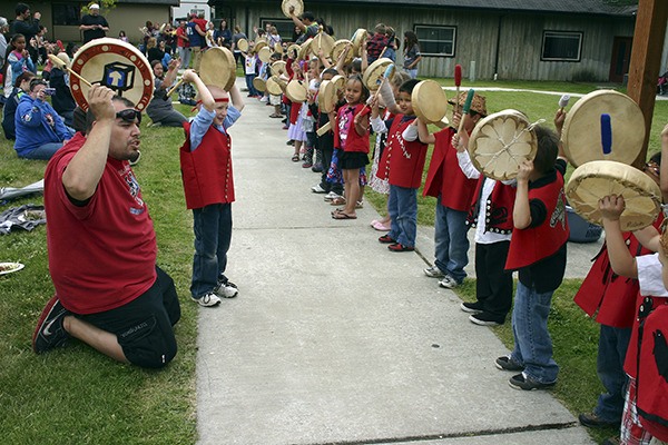 Head Start teacher Kyle Carpenter and his students raise their hands in thanks after a song at the beginning of the Port Gamble S'Klallam Head Start graduation ceremony