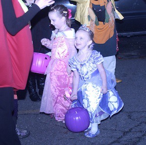 A couple of girls — dressed as princesses — make their way to a 'trunk and treat' event at A&W on Halloween night.