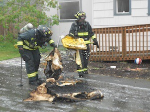 South Kitsap Fire and Rescue firefighters shift through burned materials pulled from inside a Gorst home.