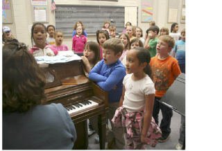 Choir teacher Susan Daun-Woodstock practices “America The Beautiful” with her students at Sidney Glen Elementary School Wednesday. The students were preparing to perform the song at an assembly honoring veterans.