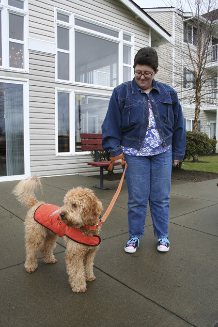 Pami Perry stands outside of her East Bremerton apartment complex Jan. 7 with her service dog Rainbow. Beginning March 15