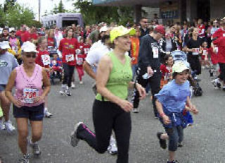 Runners wear wide grins as they cross the finish line on June 1 at the Kitsap Family Fun Run. Ridgetop Junior High School’s Jessica Sanchez won the girls’ 1-mile run while Olympic High’s John Wojtech won the boys race. Fellow Trojan Brendan Schruhl took first in the 5K event which was the culmination of a seven-week fitness program provided to more than 20