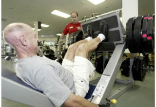 Tim Smith uses the leg press at Kitsap Family YMCA as his trainer Barry Hernandez looks on during their Wednesday morning workout session. Smith is determined to not let the fact he is blind and deaf prevent him from staying physically fit.