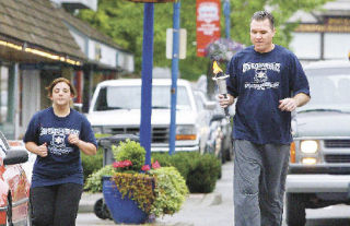 Poulsbo Police Chief Dennis Swiney (right) and Police clerk Amanda Dixon led the first two legs of the Special Olympics torch relay though Poulsbo Thursday morning.