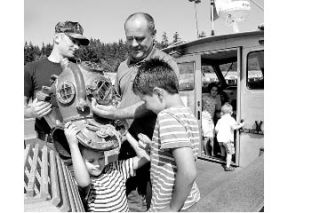 Navy diver Anthony Munson from Keyport helps Christopher Soto with a helmet fitting during the annual Touch-A-Truck in Poulsbo.