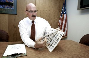 Detective Doug Dillard flips through the FBI Facial Identification Catalog. Based on witness and victim accounts