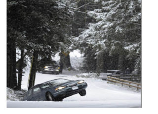 (Left) Bremerton police were called out to a multi-vehicle accident on Sheridan Road in Bremerton. The road was closed while law enforment worked to clear the road Thursday afternoon. (Right) A stranded driver waits in his car as it sits in the ditch tilted above the ground on Tracyton Boulevard NW Thursday.  (Inset) Snow piles up on decorated lamppost in Bremerton. Thursday saw accumulations of 1-3 inches