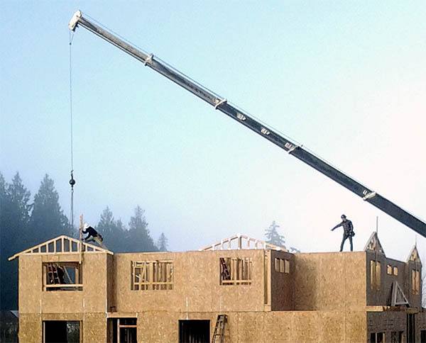 Construction workers place a truss on a home under construction at Highmark Homes’ The Villas at Caldart Heights. Depending on down payment and financing