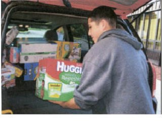 A teen volunteer from St. Gabriel’s Catholic Church loads food donations for local food banks.