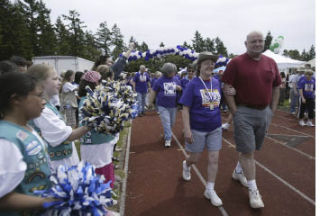 Girl Scouts from Troop 50599 wave pom-poms during last year’s Survivor’s Lap as cancer survivors take to the Central Kitsap High School track.