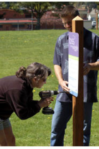 Leadership Kitsap “The Marksmen” team members Jennifer Forbes and Jeff Pfost install a sign on the trail they and their team members helped construct at Naval Avenue Early Learning Center.