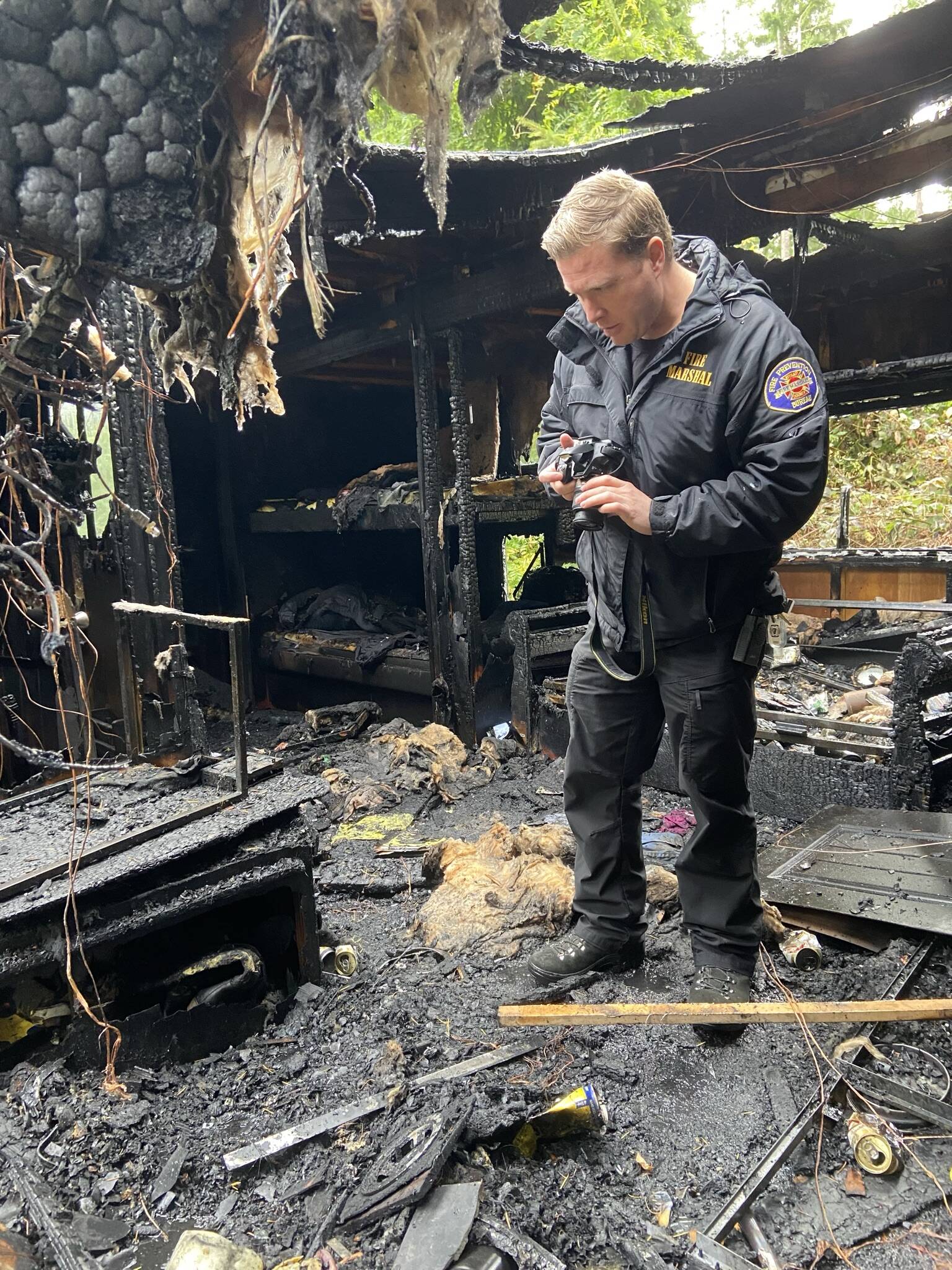 Deputy Fire Marshal Greg Gentile examines the scene and photographs key elements after a fire gutted a travel trailer Tuesday.