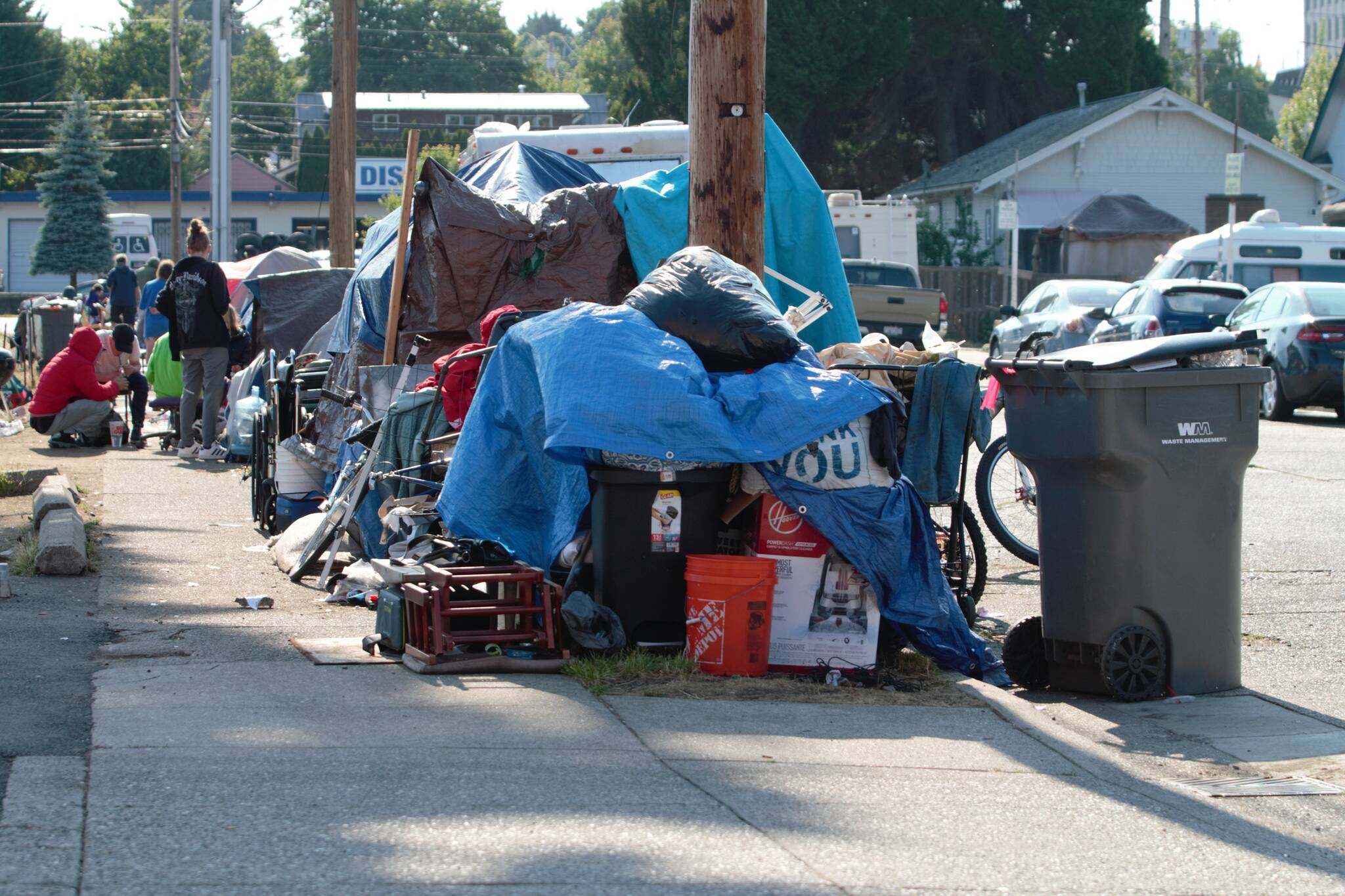 Trash is collected and put in a pile, behind which is a long line of occupied tents and tarps. Elisha Meyer/Kitsap News Group Photos