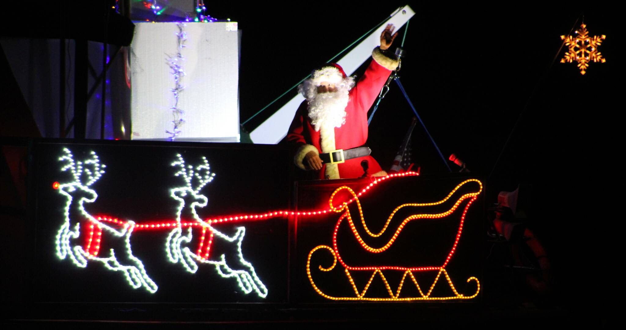 Elisha Meyer/Kitsap News Group Photos 
Santa waves to the shoreside crowd in Silverdale while the names of some of the attendees are announced as having received Christmas greetings.