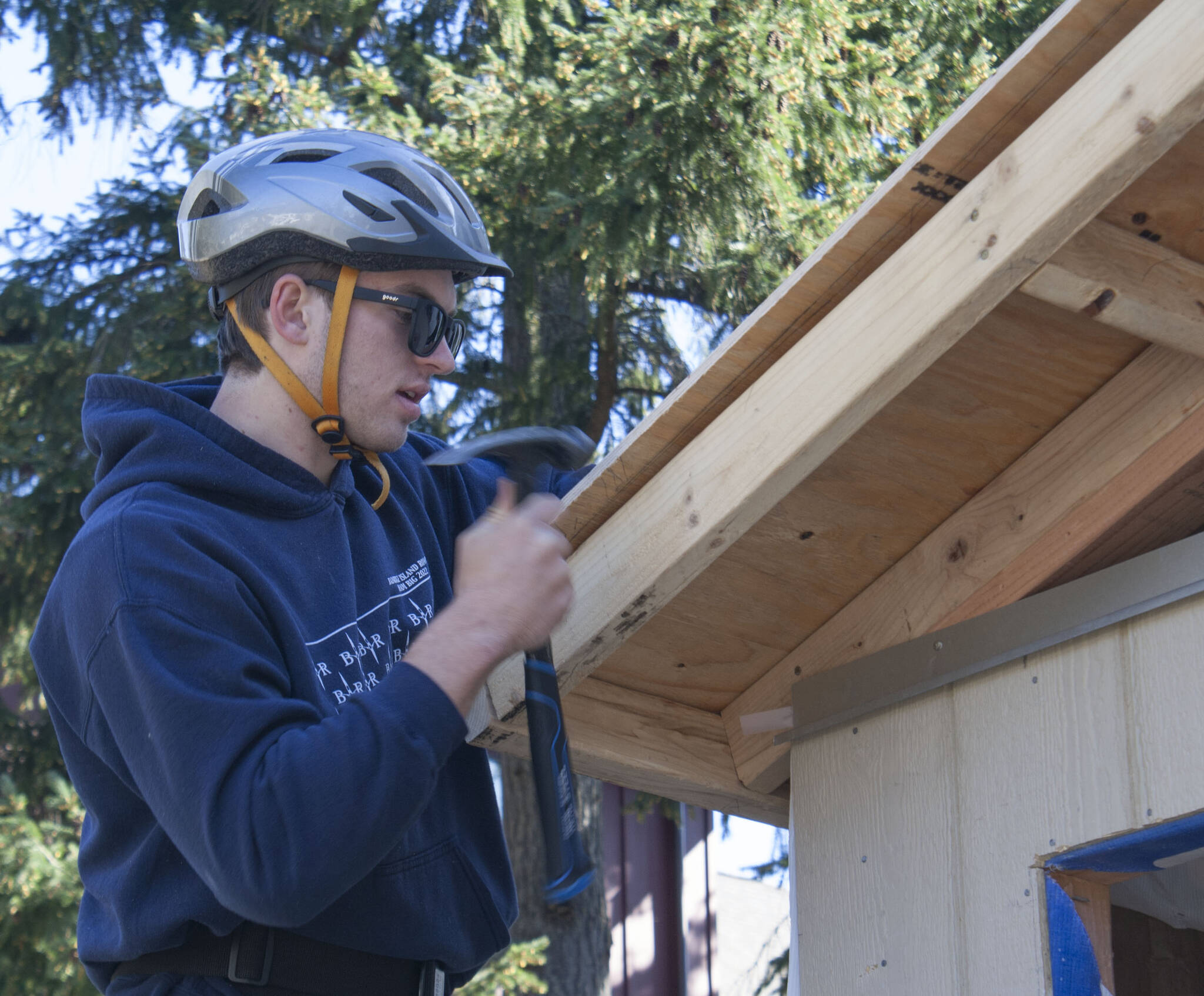 Student James Phillips secures a piece of plywood to the roof of the Hyla students’ tiny home project.