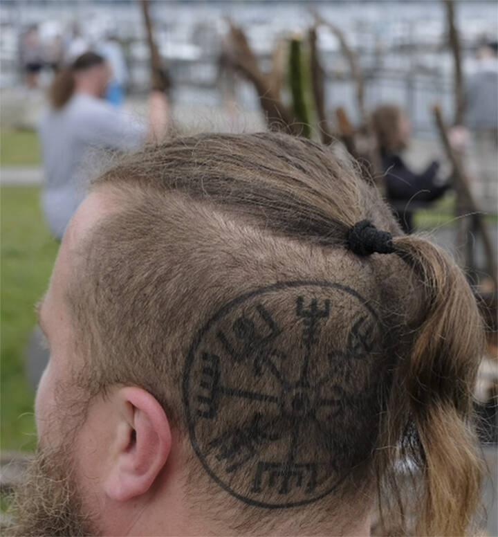 Damon Williams/Kitsap News Group photos
Brennan Webster shows his tattoo as others build the bonfire in the background.