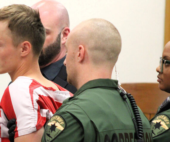 Elisha Meyer/Kitsap News Group
23-year-old double homicide suspect Seth South is restrained by shackles and a trio of correction officers in court Oct. 10. Officers began to accompany him before the judge after he made a sudden move toward the gallery of the courtroom.